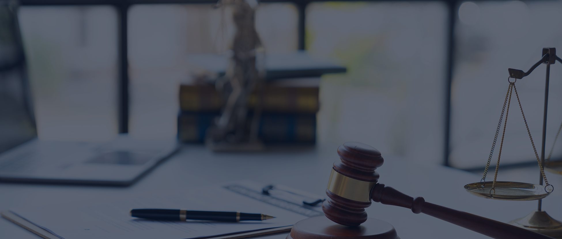 Gavel, scales of justice and a notepad on a desk beside a window
